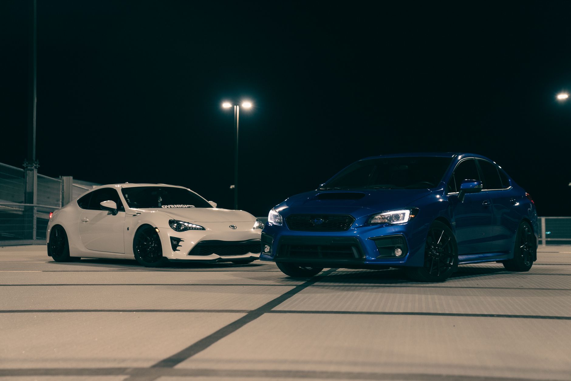 Biała i niebieska Mazda sportowa zaparkowane nocą na dachu parkingu