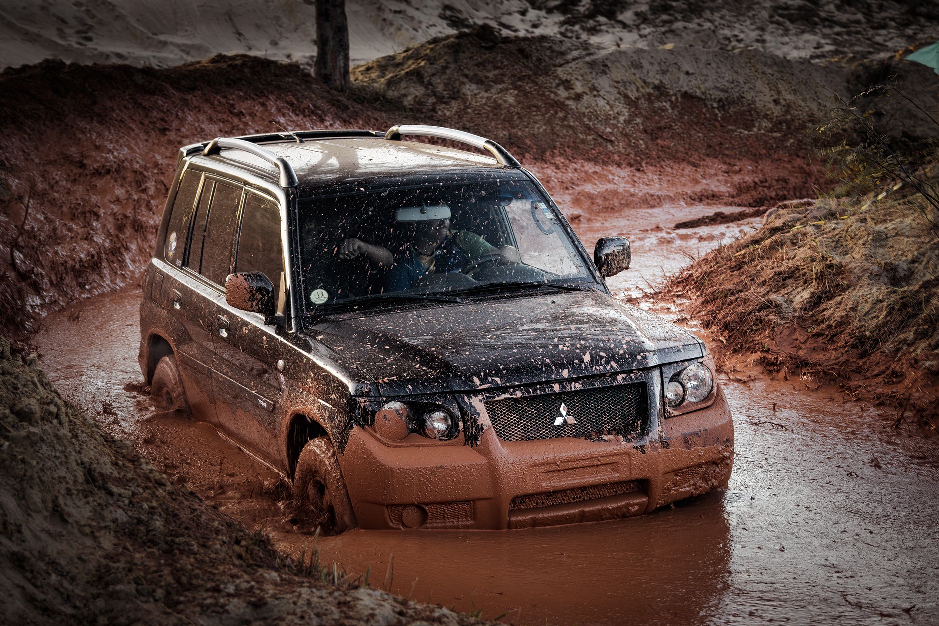Mitsubishi Pajero jedzie po błotnistym, terenowym szlaku