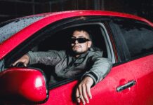 Samochody Volvo dla wysokich kierowców które modele oferują najwięcej miejsca na nogi i nad głową Wysoki mężczyzna w okularach przeciwsłonecznych siedzi w czerwonym Volvo nocą