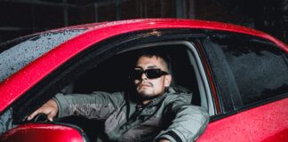 Wysoki mężczyzna w okularach przeciwsłonecznych siedzi w czerwonym Volvo nocą