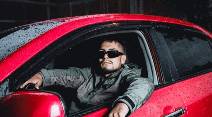 Wysoki mężczyzna w okularach przeciwsłonecznych siedzi w czerwonym Volvo nocą