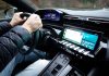 Wnętrze Toyoty z dłońmi na kierownicy i nowoczesnym kokpitem