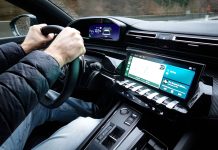 Wnętrze Toyoty z dłońmi na kierownicy i nowoczesnym kokpitem