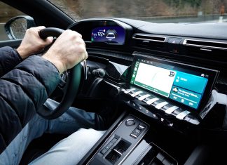 Najczęstsze mity o hybrydach Toyoty: spalanie, trwałość baterii i opłacalność zakupu Wnętrze Toyoty z dłońmi na kierownicy i nowoczesnym kokpitem