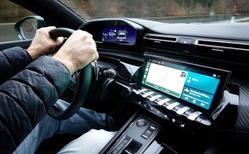 Wnętrze Toyoty z dłońmi na kierownicy i nowoczesnym kokpitem